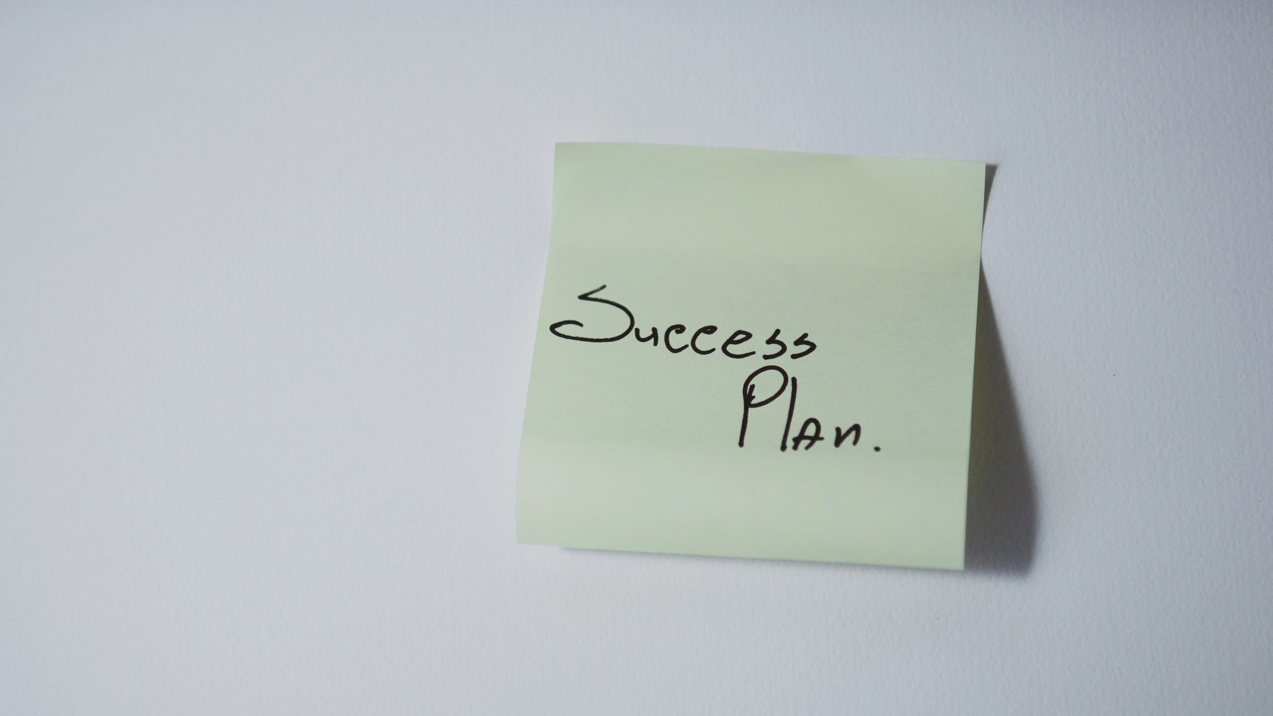 A sticky note reading Success Plan, representing goal-setting and planning